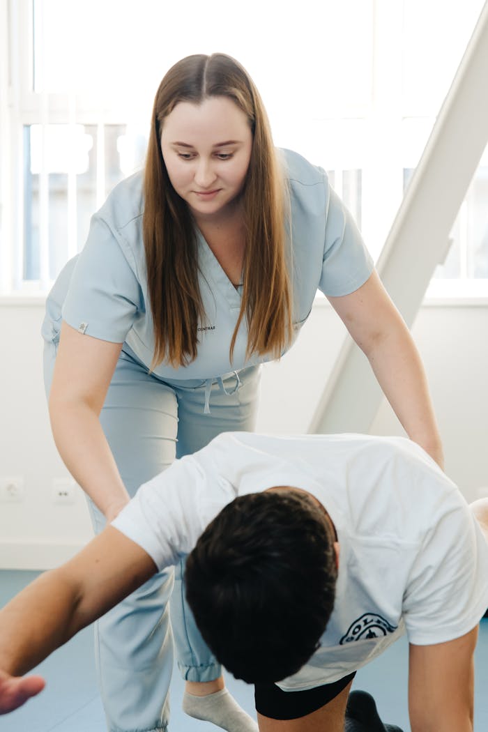 A physiotherapist assists a client in an exercise during a therapy session indoors.